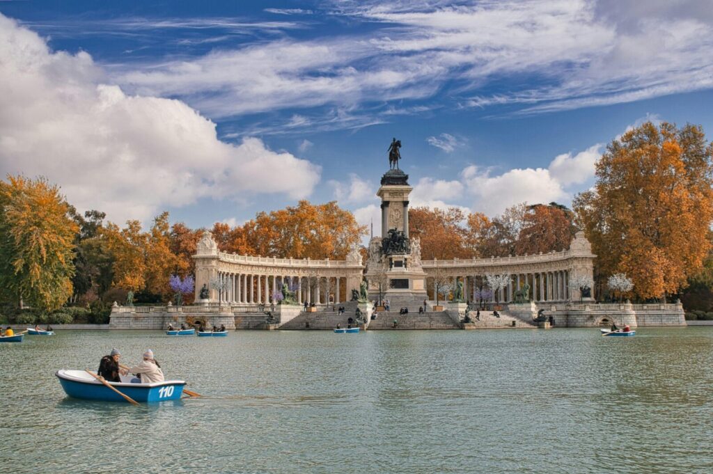 Scenic autumn landscape of Retiro Park monument with boats on the lake.