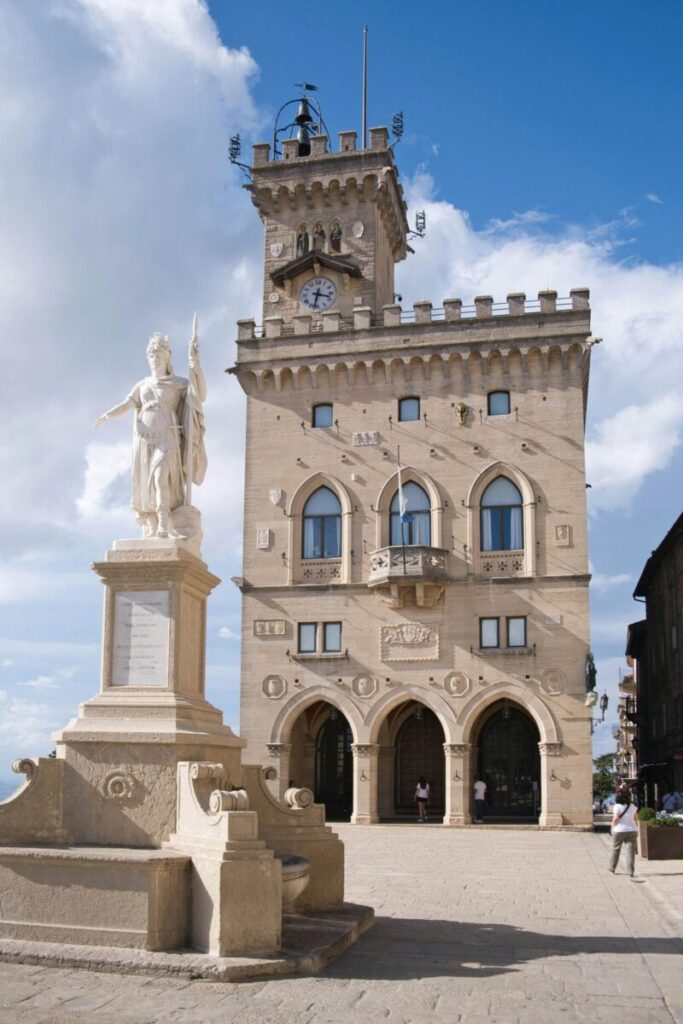 Charming medieval tower with a clock and statue under blue sky in San Marino.